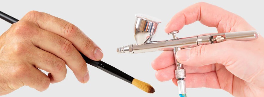 Hand holding a paintbrush facing another with an airbrush, symbolizing choice between traditional and modern techniques.