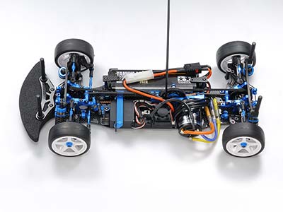 RC car chassis top view with exposed components and wiring, featuring blue and black parts, white wheels.